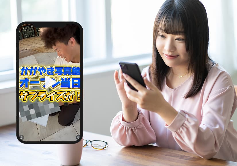 女性が手にしたスマートフォンにテロップ入り動画が映り、興味深そうに見つめている様子